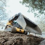 Skid steer loader grading uneven ground for construction project