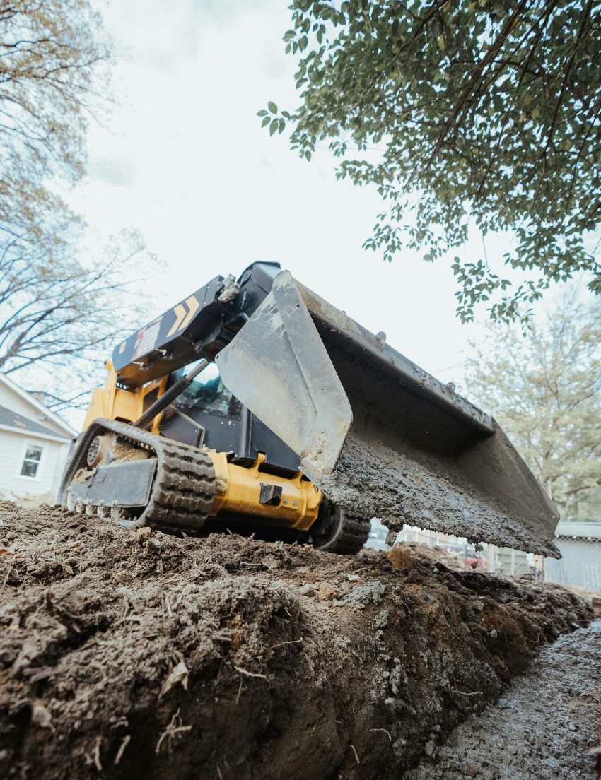 Skid steer loader grading uneven ground for construction project