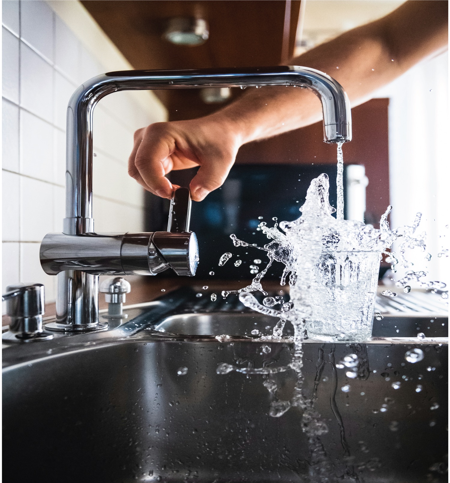 Handyman installing a new chrome faucet in a modern bathroom sink. Faucet installation services for kitchens and bathrooms in Surrey, BC