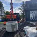 Mini excavation equipment off loading a sump basin.