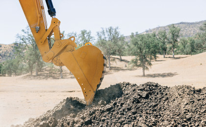 Mini excavator levelling, grading uneven backyard in preparation for landscaping project