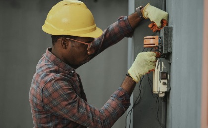 Electrician installing a new wall plug socket in a residential living room.